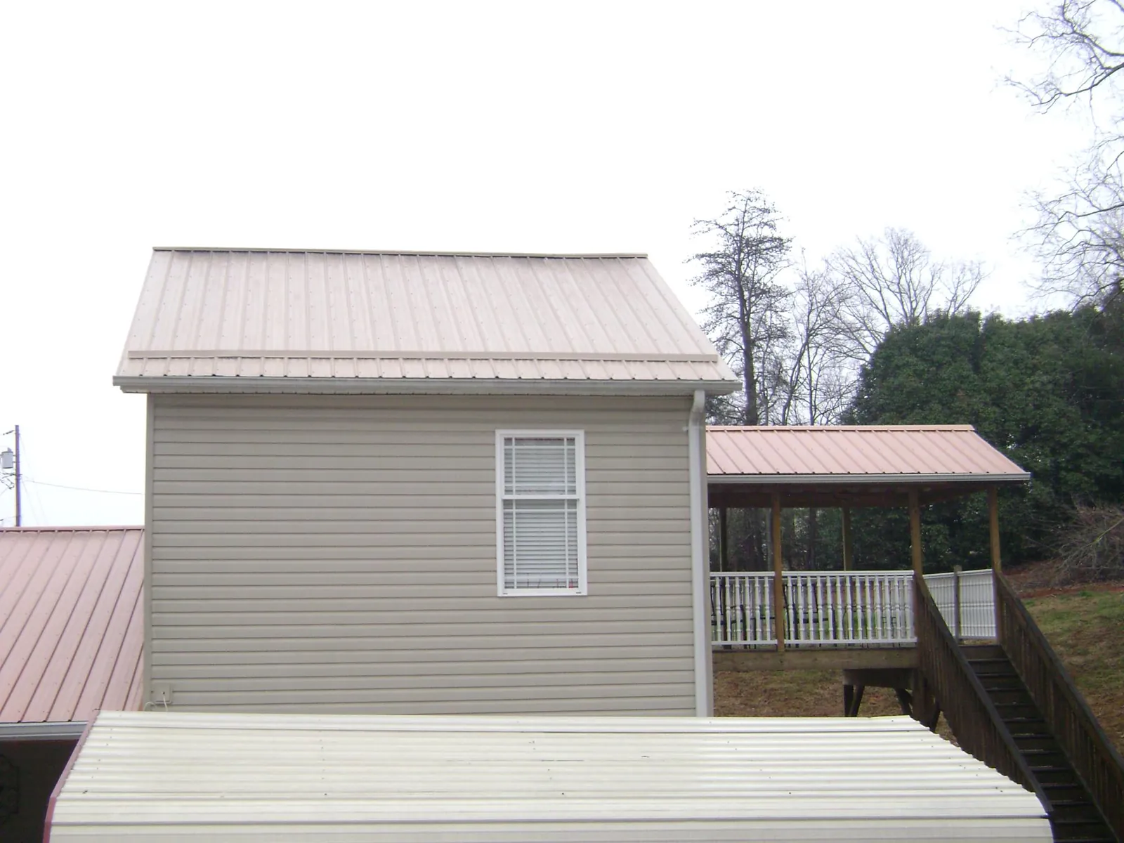 Tan metal roofs on a two story addition and attached porch, from a Roof Replacement job in Fullerton