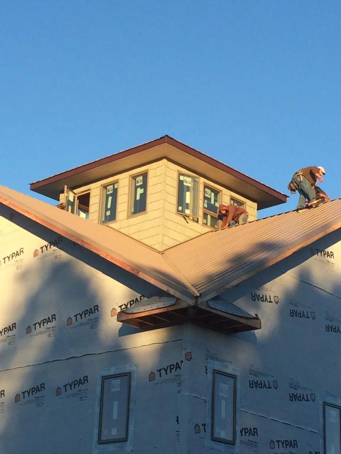 Roofers working around a rooftop cupola on a new metal roof at sunset — Roof Waterproofing in Fullerton by Roofing Brothers